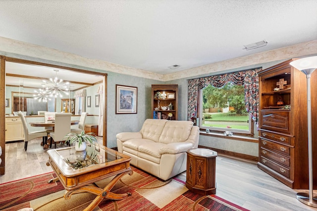 living room featuring a textured ceiling, light hardwood / wood-style floors, and a chandelier