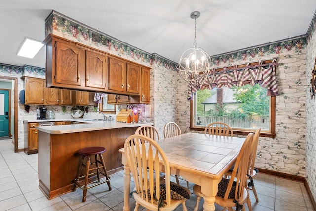 tiled dining room featuring an inviting chandelier, a skylight, and sink