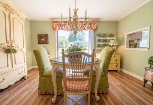 dining space with wood-type flooring, a notable chandelier, and crown molding