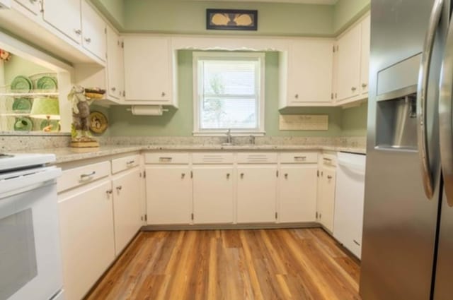 kitchen featuring white cabinets, light wood-type flooring, light stone countertops, and white appliances