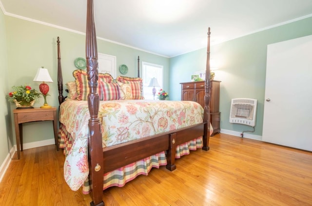 bedroom with crown molding, light hardwood / wood-style floors, and heating unit