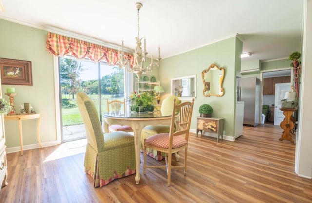 dining room with crown molding, an inviting chandelier, and hardwood / wood-style flooring