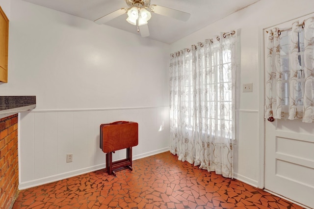 sitting room with wood walls and ceiling fan