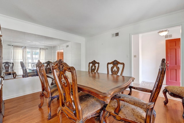 dining space with light hardwood / wood-style flooring and crown molding