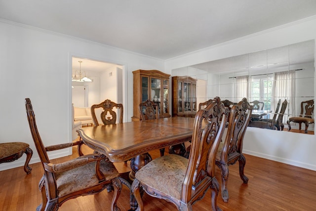 dining room featuring wood-type flooring, ornamental molding, and a chandelier