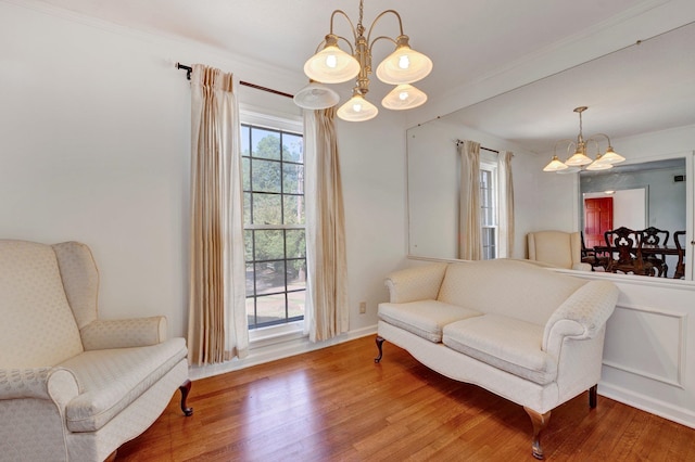 sitting room featuring wood-type flooring, an inviting chandelier, and ornamental molding