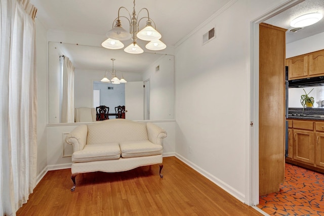 living area with wood-type flooring, crown molding, and a notable chandelier