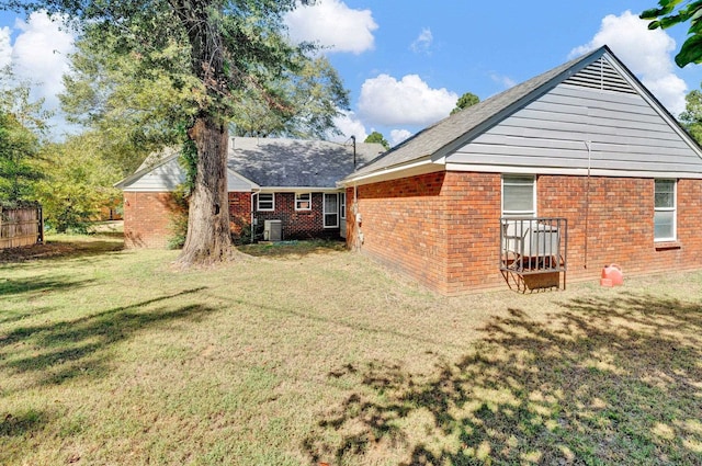 rear view of property with a lawn and central AC