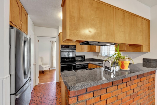 kitchen featuring dark stone countertops, kitchen peninsula, a textured ceiling, black appliances, and sink