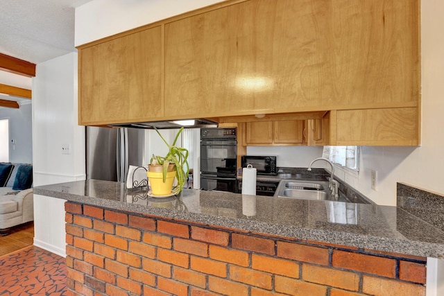 kitchen with double oven, dark stone counters, sink, and kitchen peninsula