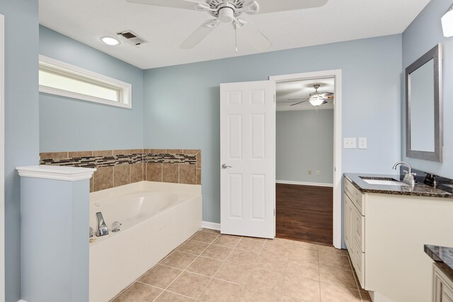 bathroom with tile patterned floors, ceiling fan, a bath, and vanity