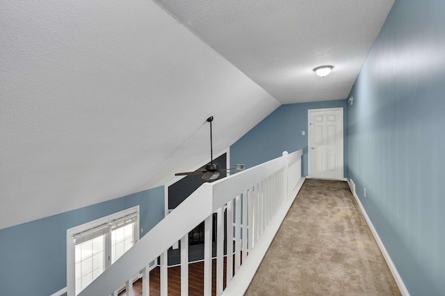 hall featuring light carpet, a textured ceiling, and vaulted ceiling