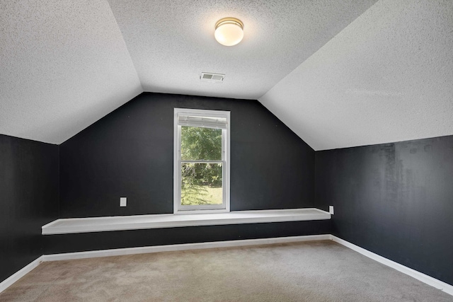 additional living space featuring vaulted ceiling, a textured ceiling, and carpet floors