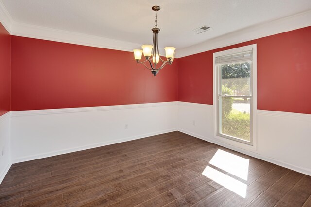 spare room with an inviting chandelier, ornamental molding, and dark hardwood / wood-style flooring