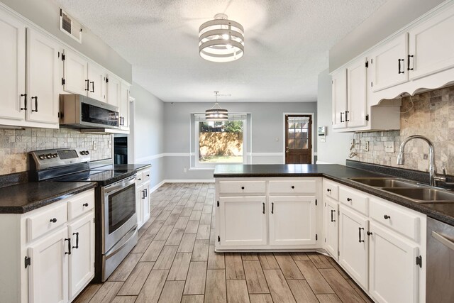 kitchen featuring appliances with stainless steel finishes, light wood-type flooring, white cabinetry, and sink