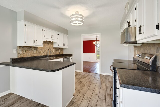 kitchen with light wood-type flooring, kitchen peninsula, white cabinetry, and stainless steel appliances