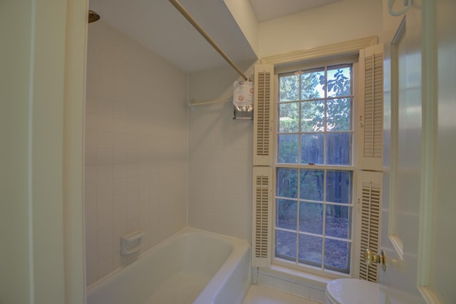 bathroom featuring tiled shower / bath combo and toilet