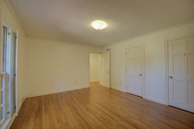 unfurnished bedroom with ornamental molding, a textured ceiling, and hardwood / wood-style floors