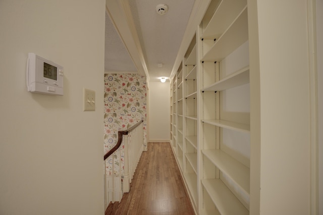 corridor with hardwood / wood-style flooring and crown molding