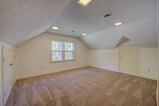 bonus room with vaulted ceiling, a textured ceiling, and carpet flooring