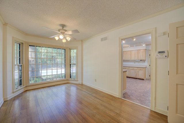 unfurnished room featuring ceiling fan, a textured ceiling, light hardwood / wood-style flooring, and ornamental molding