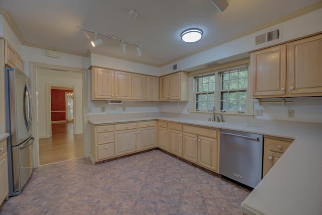 kitchen featuring appliances with stainless steel finishes, a textured ceiling, light brown cabinetry, and sink