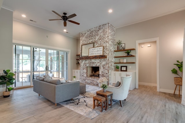 living room with light hardwood / wood-style flooring, ceiling fan, a fireplace, and crown molding