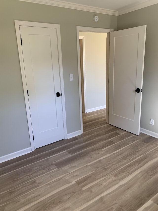 unfurnished bedroom featuring a closet, crown molding, and light hardwood / wood-style flooring