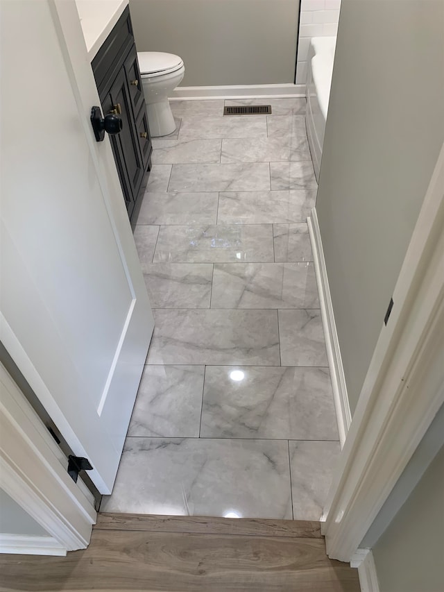 bathroom with vanity, a bath, and toilet