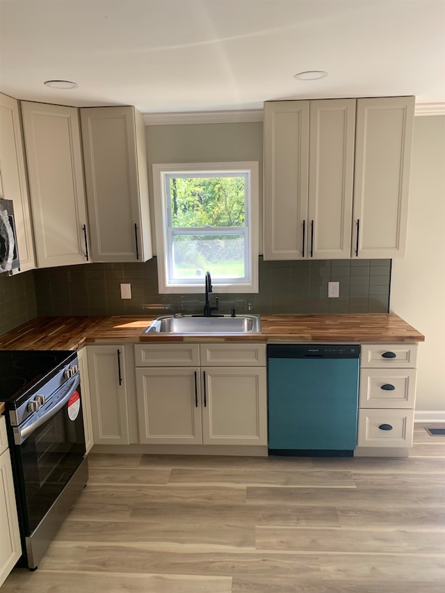 kitchen featuring backsplash, sink, light wood-type flooring, appliances with stainless steel finishes, and butcher block countertops