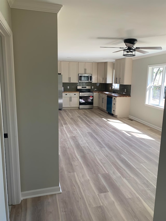 kitchen with crown molding, light hardwood / wood-style flooring, stainless steel appliances, and sink