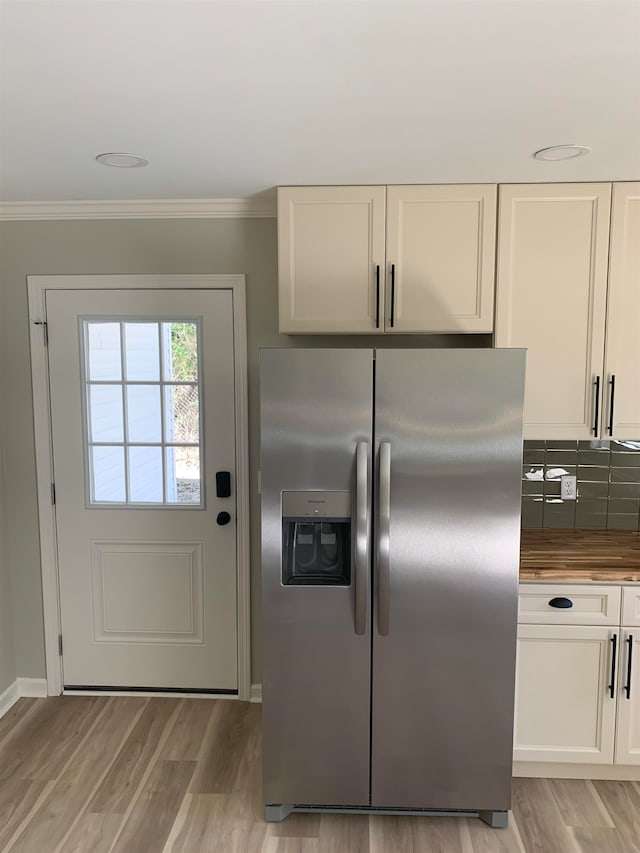 kitchen featuring white cabinetry, light wood-type flooring, stainless steel fridge with ice dispenser, and ornamental molding