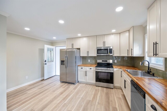 kitchen with backsplash, sink, dark hardwood / wood-style floors, ornamental molding, and appliances with stainless steel finishes