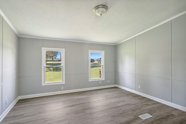 spare room with wood-type flooring, a textured ceiling, and crown molding