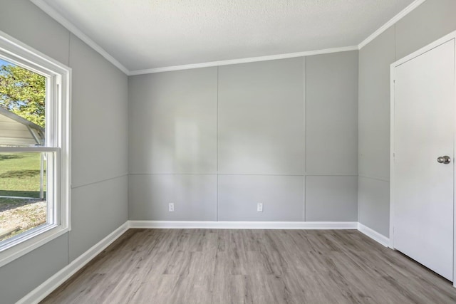 spare room with light hardwood / wood-style flooring, a textured ceiling, and ornamental molding