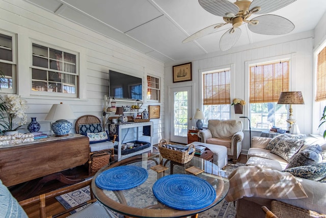 living room with ceiling fan, hardwood / wood-style flooring, and wooden walls