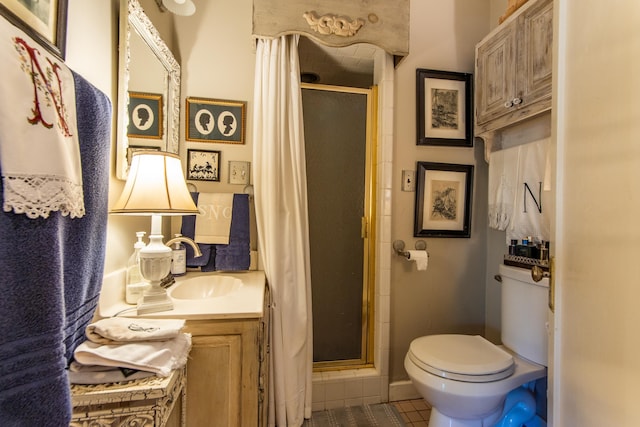 bathroom with vanity, tile patterned flooring, a shower with shower door, and toilet