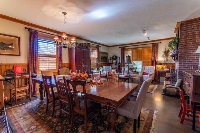 dining space with a notable chandelier, wood walls, a textured ceiling, and crown molding