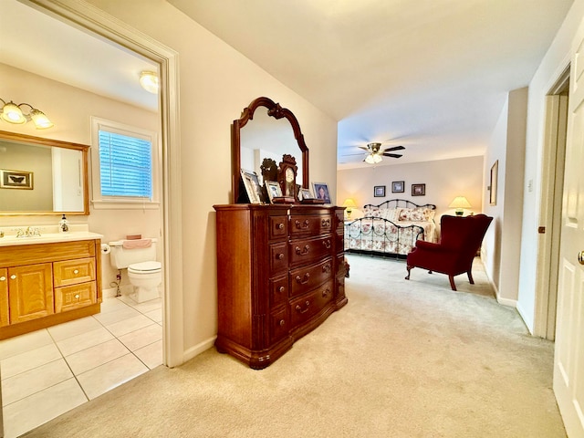 carpeted bedroom with ensuite bath, ceiling fan, and sink