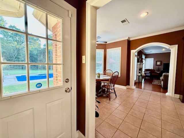 doorway with crown molding, a healthy amount of sunlight, and light tile patterned flooring