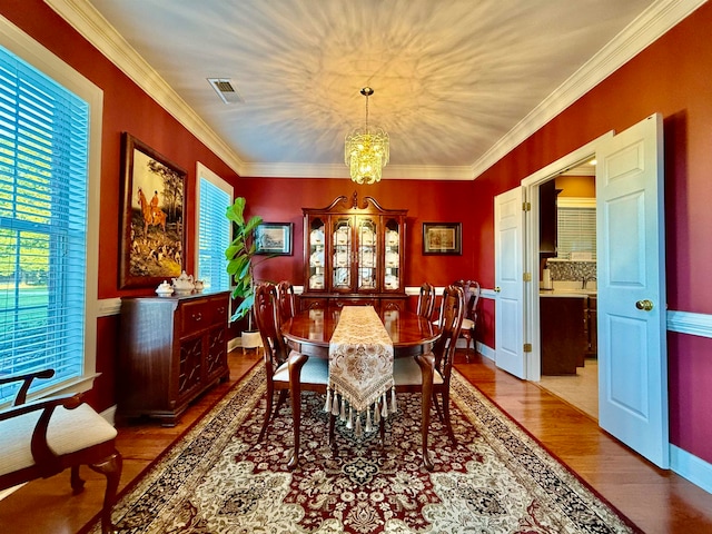 dining area featuring a chandelier, light hardwood / wood-style floors, and crown molding