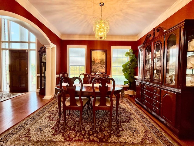 dining space featuring an inviting chandelier, decorative columns, dark hardwood / wood-style floors, and crown molding