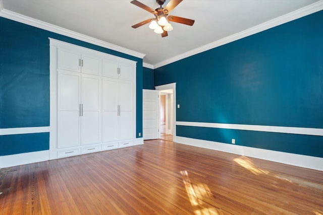 unfurnished bedroom with ceiling fan, ornamental molding, a closet, and hardwood / wood-style floors