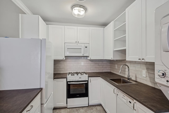 kitchen with stacked washer / dryer, tasteful backsplash, sink, white cabinetry, and white appliances