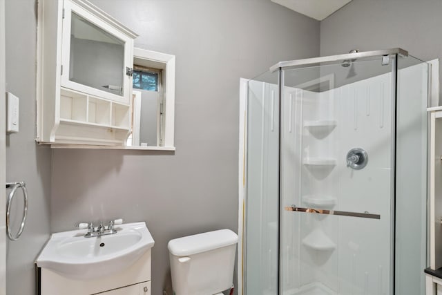 bathroom with a shower with shower door, vanity, and toilet