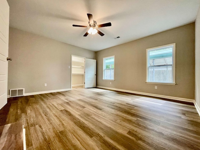 unfurnished bedroom with hardwood / wood-style floors, a spacious closet, ceiling fan, and a closet