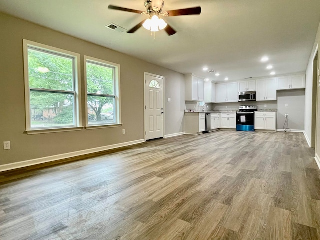 kitchen with ceiling fan, appliances with stainless steel finishes, light hardwood / wood-style floors, and white cabinetry