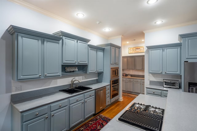 kitchen featuring hardwood / wood-style flooring, appliances with stainless steel finishes, sink, and decorative backsplash