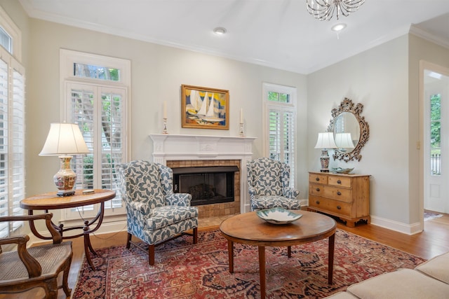 sitting room with ornamental molding, a tiled fireplace, and hardwood / wood-style floors