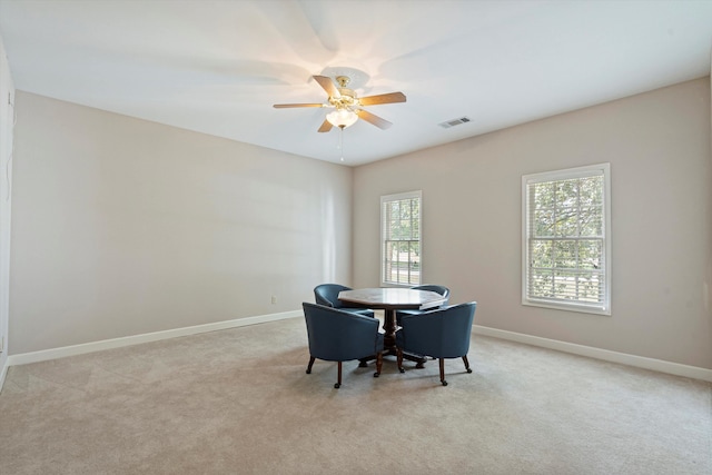 dining room with ceiling fan and light colored carpet